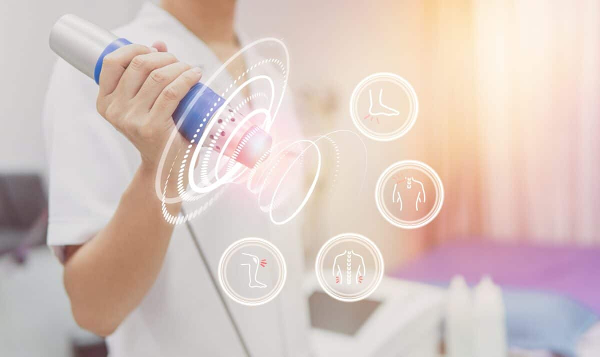 Physiotherapist using shockwave with virtual health care symbol and pain icons medical on interface. modern virtual screen interface, health problem and medical technology concept.