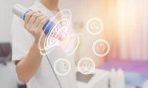 Physiotherapist using shockwave with virtual health care symbol and pain icons medical on interface. modern virtual screen interface, health problem and medical technology concept.