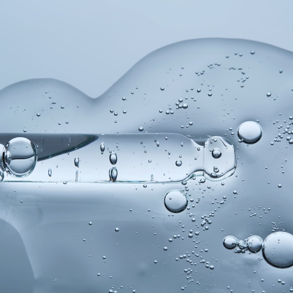 Abstract close-up image of clear liquid with suspended air bubbles against a soft blue background, representing semaglutide therapy, hydration, and modern medical wellness treatments.